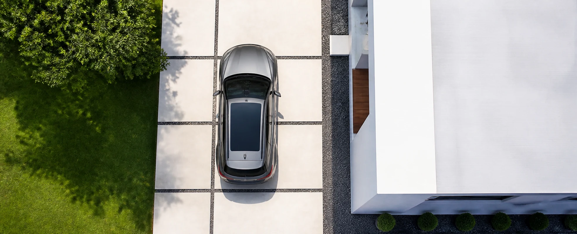 Clean top-down view of a modern car parked in a clearly marked driveway beside a contemporary home