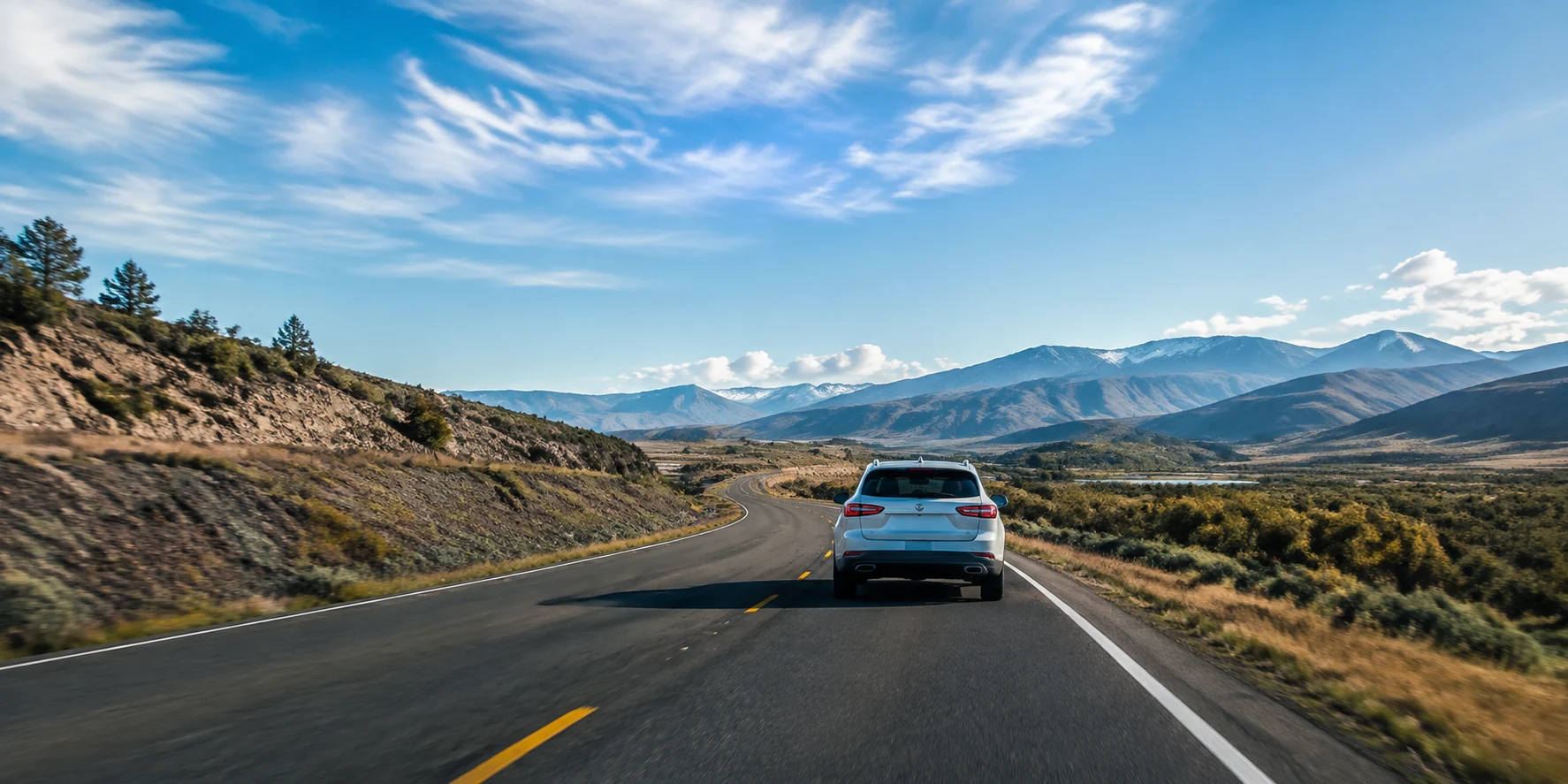 Long scenic highway with one modern car travelling toward a bright horizon